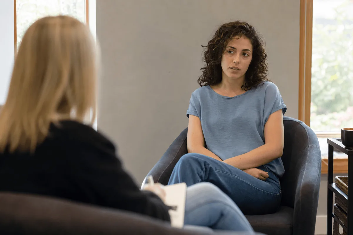 A calm, dimly lit room with soft seating, arranged to reduce sensory overload during therapy