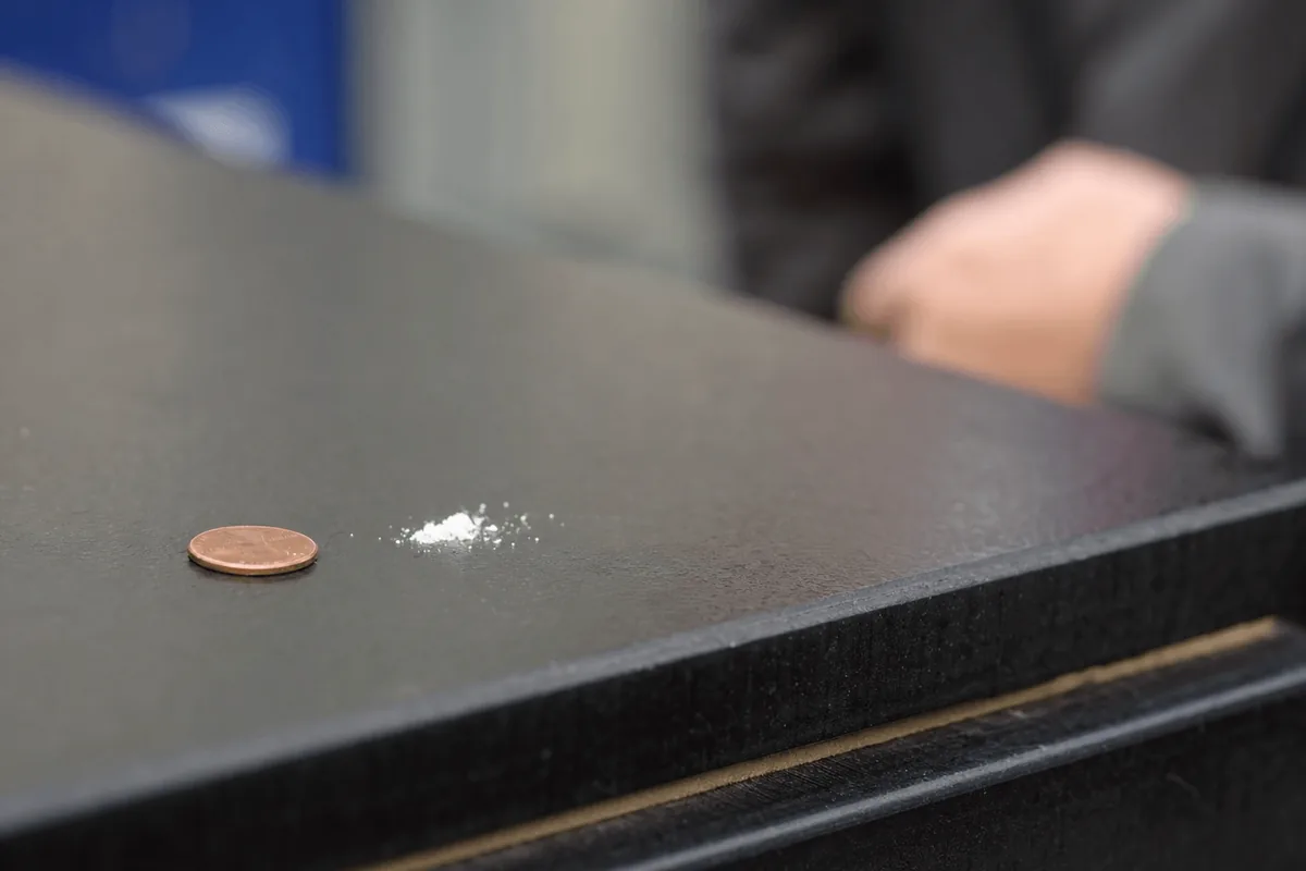 Two milligrams of powder beside a coin to show how small a potentially lethal dose of fentanyl is